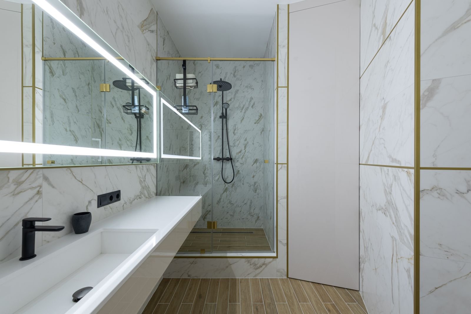 Modern bathroom with marble tiled walls, glass shower and ceramic sink